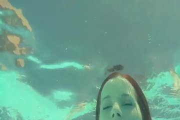 Red-haired beauty swims in the pool naked